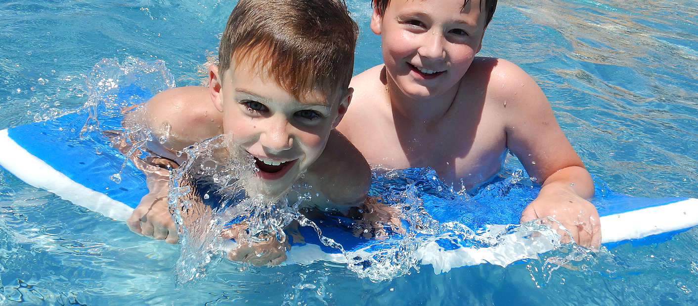 zwei Jungs schwimmen mit Schwimbrett Frei- und Seebad Fischbach