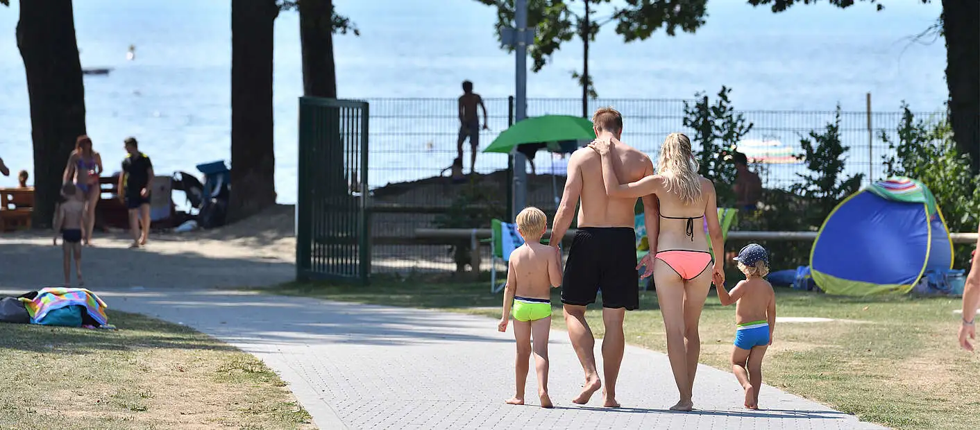 Familie läuft durch Frei- und Seebad Fischbach