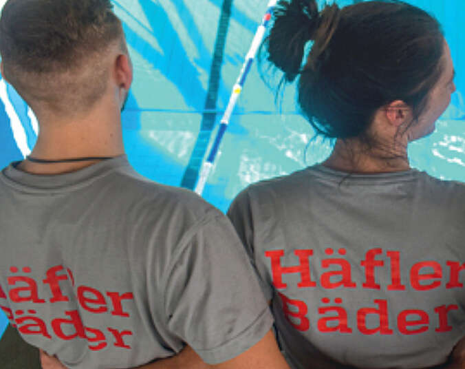 Zwei junge Menschen von hinten schauen auf ein Schwimmbecken