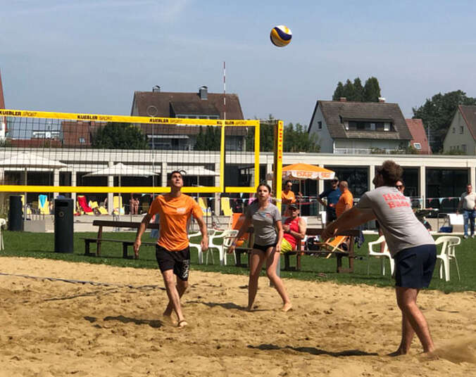 Personen spielen Volleyball auf Sand.