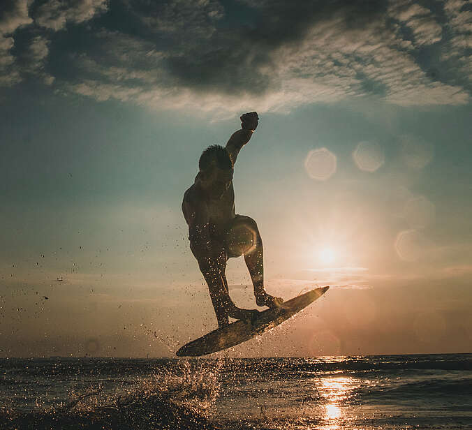 Person auf einem Skimboard vor Sonnenuntergang