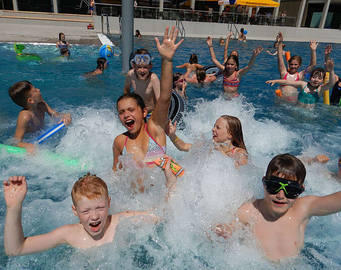 Kinder springen aus Wasser in Schwimmbecken hoch