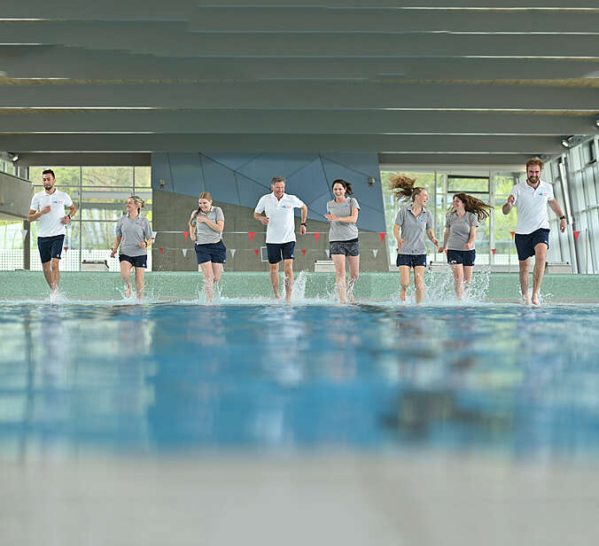 Mitarbeiter rennen durch das Wasser im Sportbad