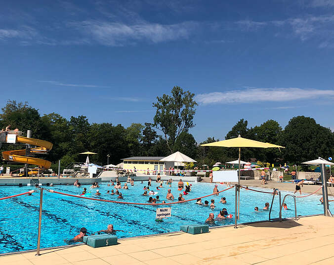 Blaues Wasser mit vielen Badenden im Schwimmbecken